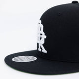 Black snapback cap side view with large white DBK logo and round 4FIFTY patch.
