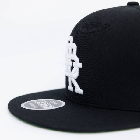 Black snapback cap side view with large white DBK logo and round 4FIFTY patch.