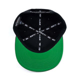 Black snapback cap with green underside brim and printed logo inside