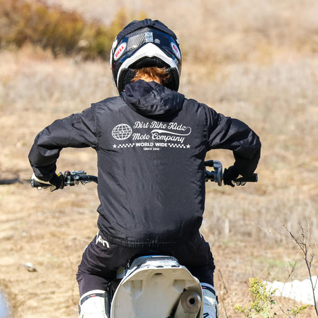 Black hooded youth windbreaker with chest graphic, worn over motorcycle gloves