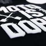Close-up of white Moto Is Dope lettering on black youth tank top
