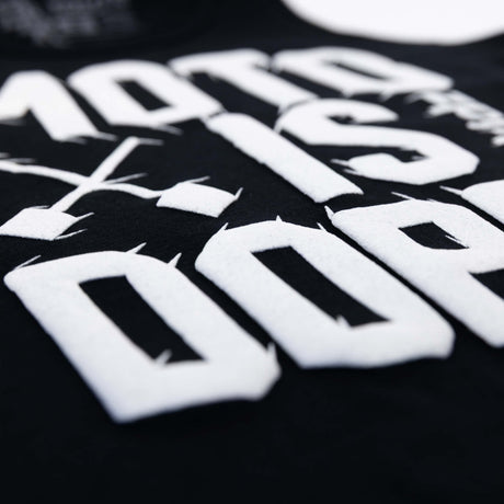 Close-up of white Moto Is Dope lettering on black youth tank top