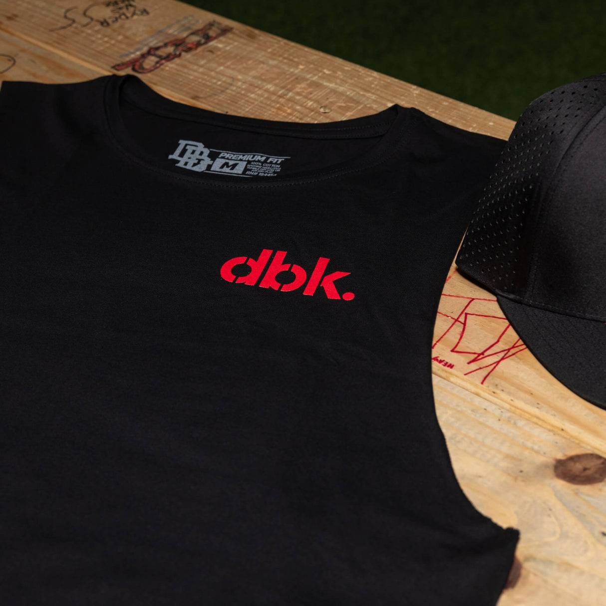 Black tank top chest close-up with red dbk. logo and crew neckline