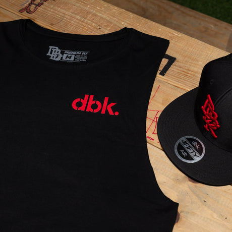 Black tank top with red dbk. logo and neckline label, plus nearby black cap