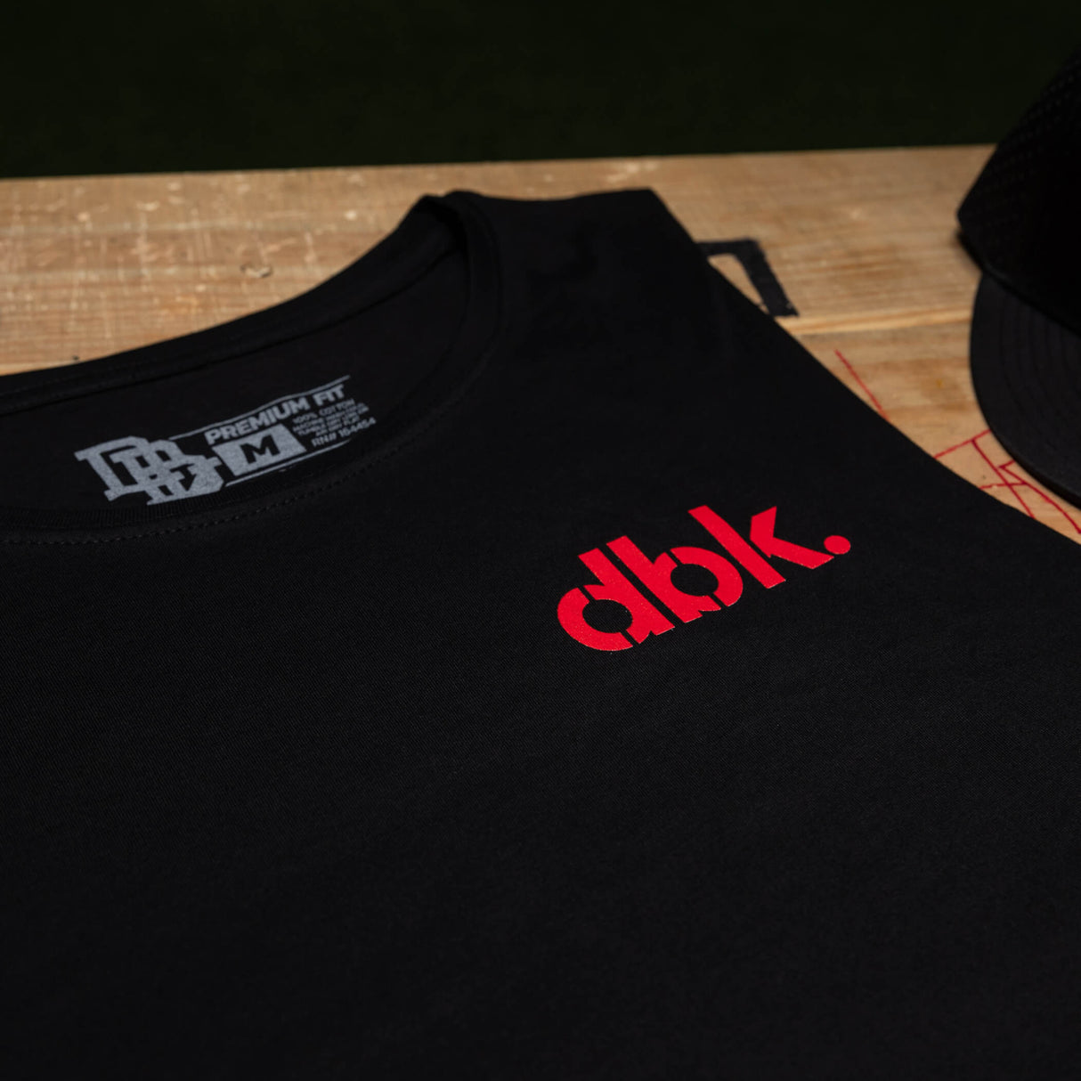 Black tank top chest close-up with red dbk. logo and neckline label
