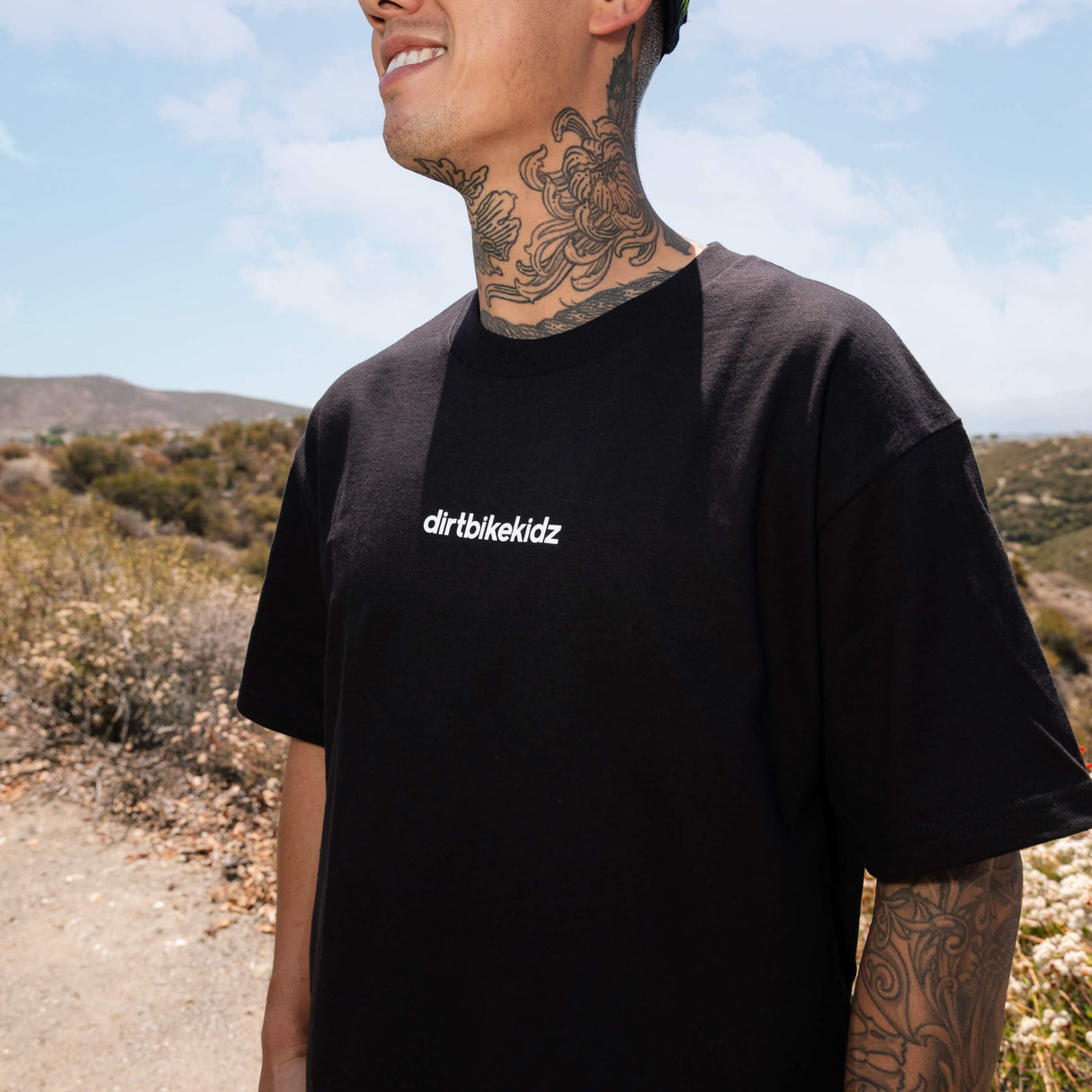 Black crewneck tee on wearer, white 'dirtbikekidz' chest print