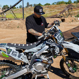 Black snapback hat worn by a rider on a dirt bike.