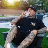 Black graphic T-shirt worn outdoors with DBK logo printed on the chest