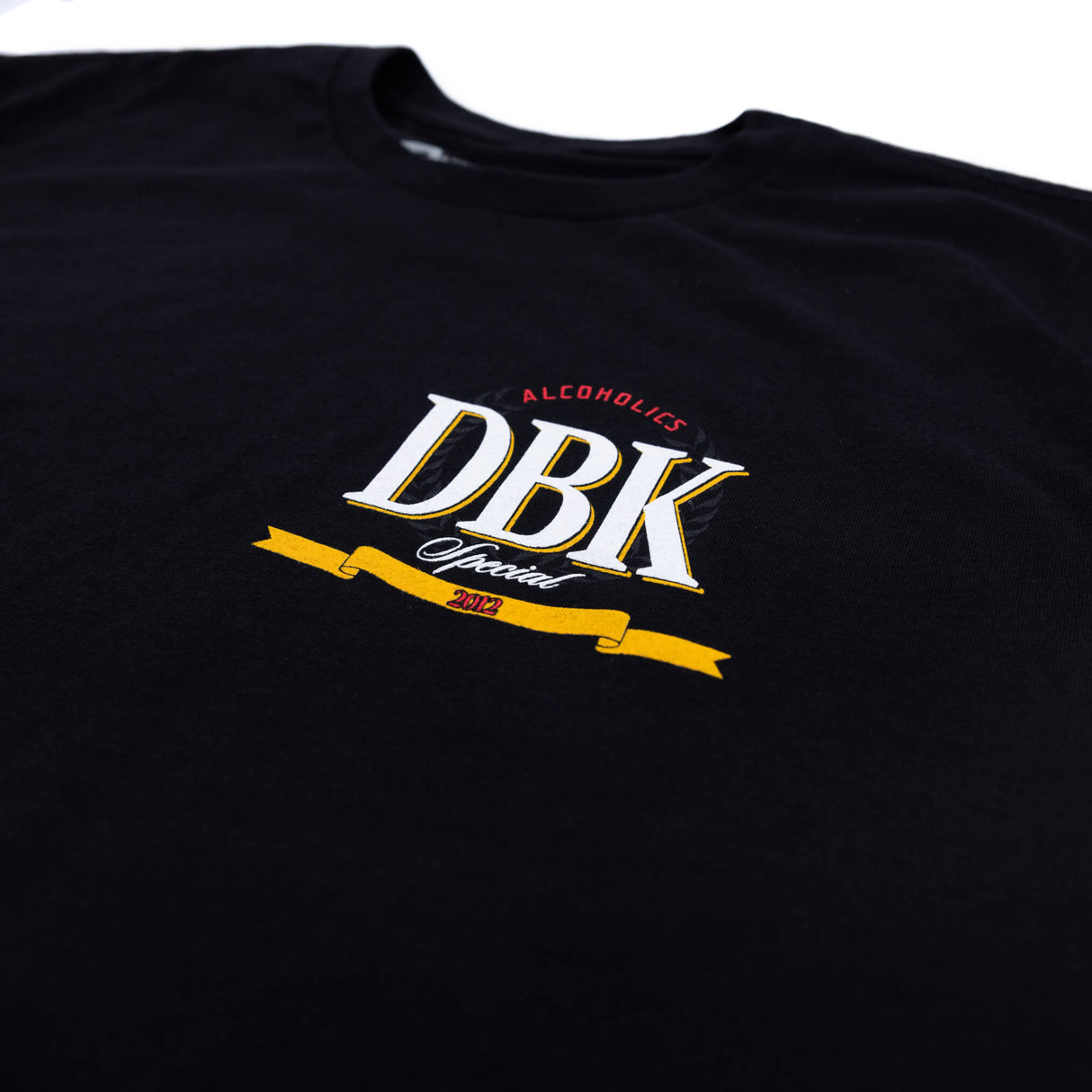 Black T-shirt back detail with vertical yellow lettering and small DBK emblem near shoulder