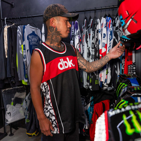 Sleeveless black jersey tank with red dbk logo band and white-red collar trim.
