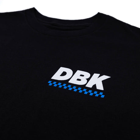 Black Balance Tee close-up: DBK logo with blue check stripe detail.
