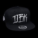 Black snapback cap front view with large white DBK graffiti-style logo