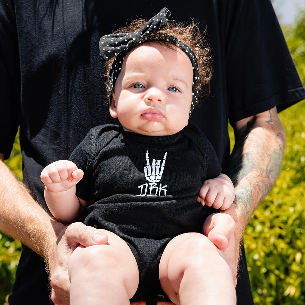 Black baby bodysuit on infant, white hand graphic on the chest