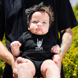 Black baby bodysuit on infant, white hand graphic on the chest