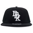 Black snapback cap with centered white embroidered DBK logo and curved brim