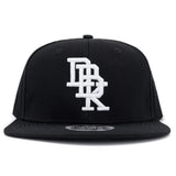Black snapback cap with centered white embroidered DBK logo and curved brim