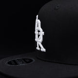 Black snapback cap side profile with white DBK embroidery near the brim