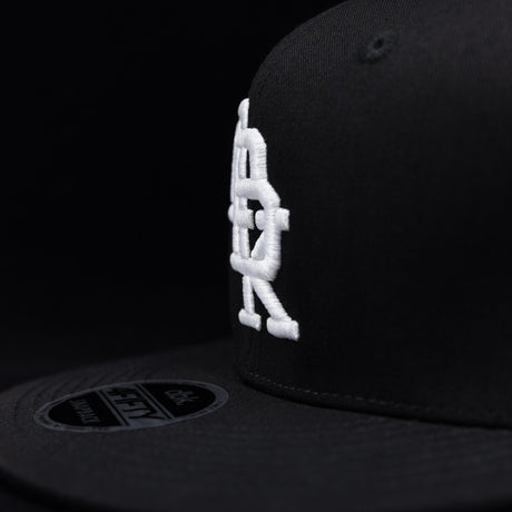 Black snapback cap side profile with white DBK embroidery near the brim