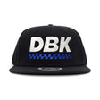 Black snapback cap with large DBK lettering and blue check stripe under it