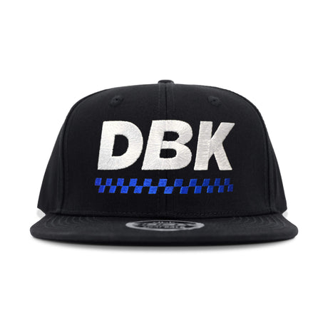Black snapback cap with large DBK lettering and blue check stripe under it