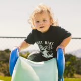 Black toddler T-shirt with front bike rider graphic, child sitting on a slide