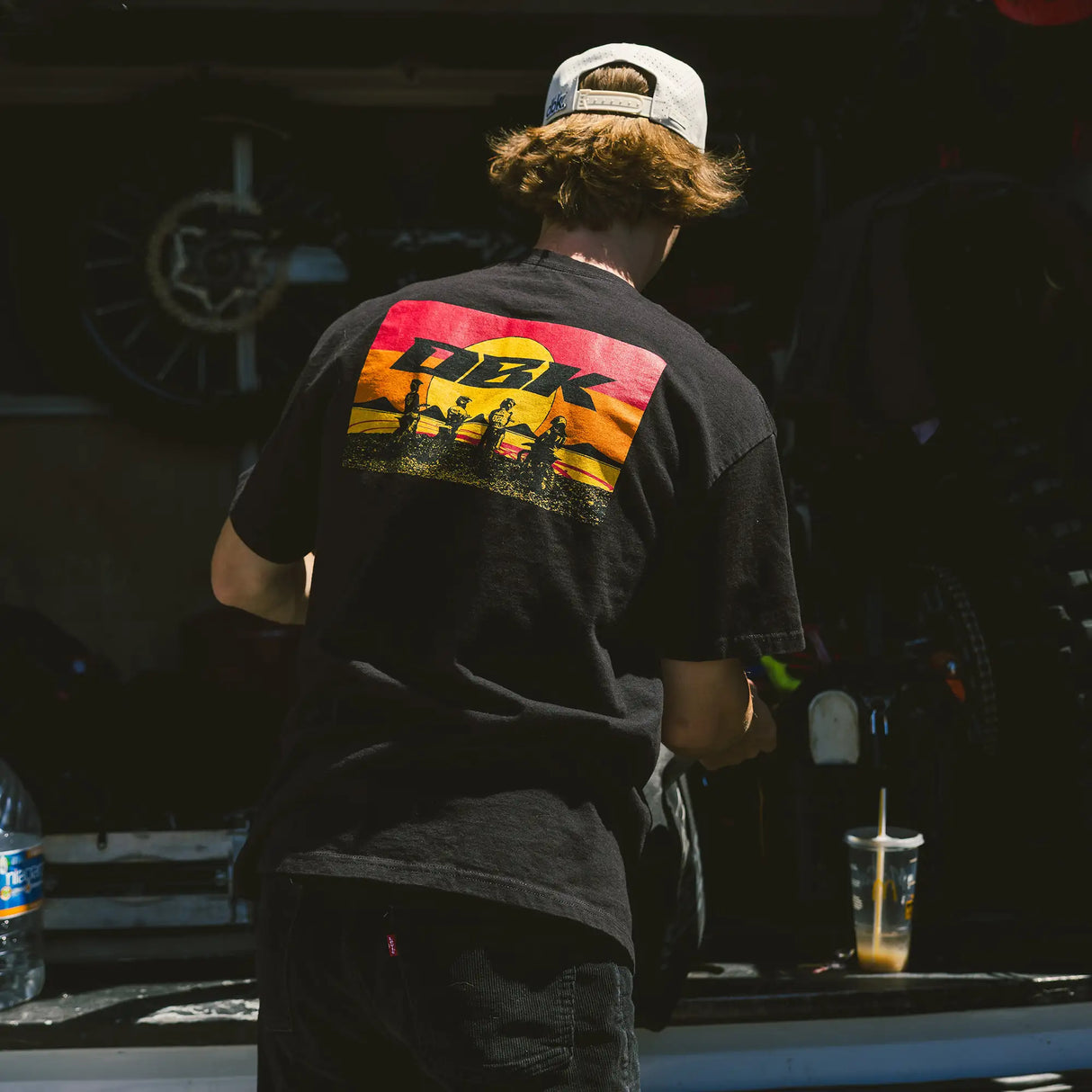 Black crewneck T-shirt with large DBK graphic on the back, worn by a person