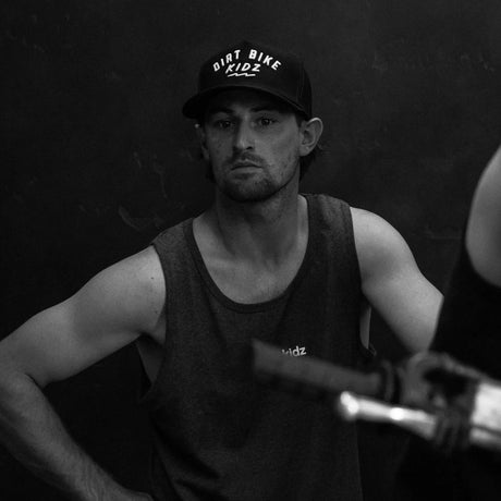 Black “Dirt Bike Kidz” cap on a man wearing a sleeveless shirt