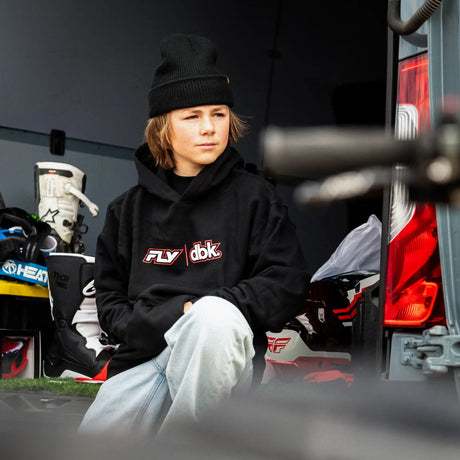 Black youth hoodie with FLY dbk chest logo, worn with light jeans
