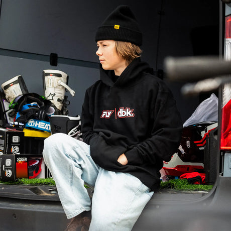Youth black hoodie with FLY dbk chest logo, worn with jeans and beanie
