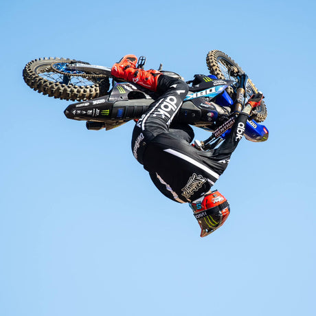 Black riding pants with white stripe details, shown while in midair