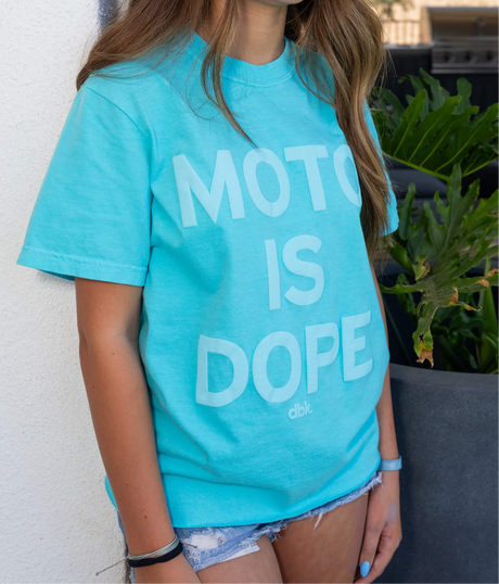 Women’s teal graphic T-shirt with white “Moto is Dope” text print, crew neckline.