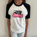 Raglan T-shirt chest graphic: Bikes Over Barbies in pink and black