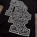 Close-up of black youth tee with white patterned letter graphic and small icon details