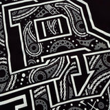 Front graphic close-up on black youth tee: white decorative letter with dots and lines