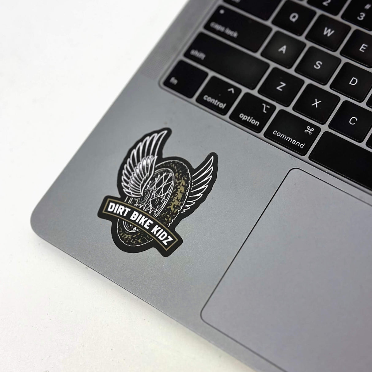 Single winged dirt bike logo sticker with DIRT BIKE KIDZ text on a gray laptop lid