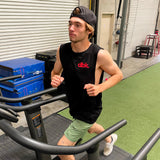 Black dbk. tank top worn by a man with green shorts and a dark cap