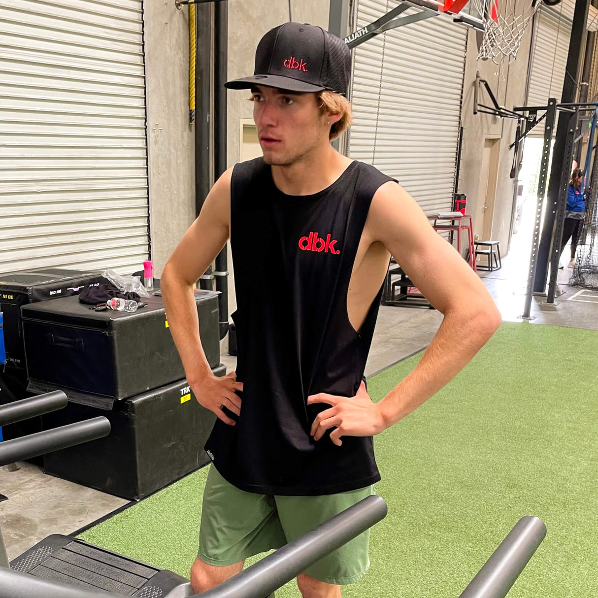 Black dbk. tank top worn by a man in an indoor gym setting