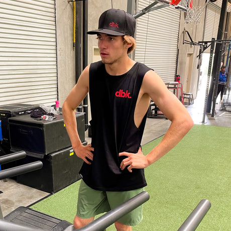 Black dbk. tank top worn by a man in an indoor gym setting