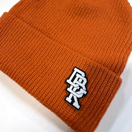 Close-up of rust orange beanie knit texture with logo patch