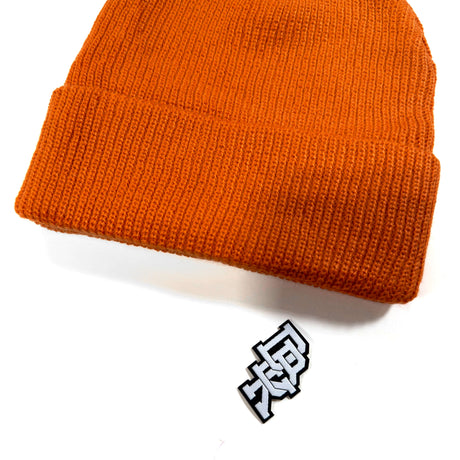 Rust orange beanie showing ribbed knit and small logo patch detail