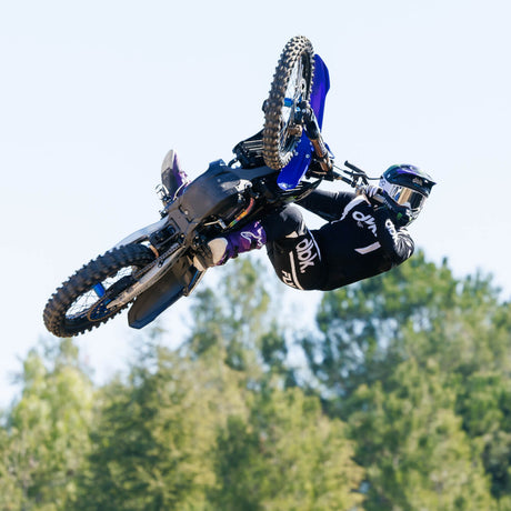 Black motocross pants with white vertical stripe, worn during riding jump