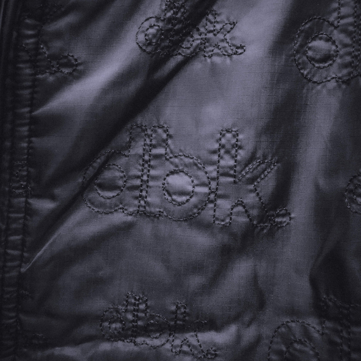 Black jacket fabric with diamond quilt stitching and raised circular appliques