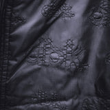 Black jacket fabric with diamond quilt stitching and raised circular appliques