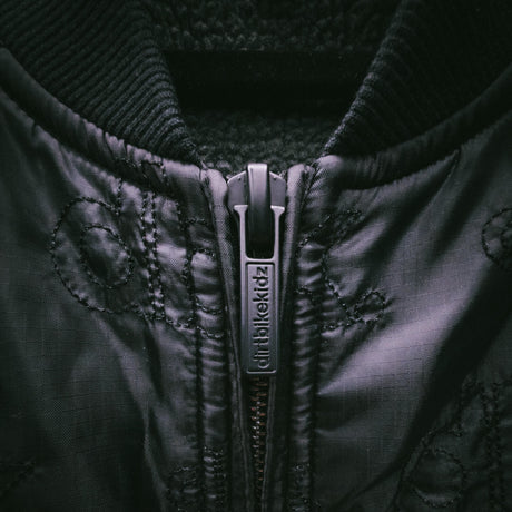 Black jacket zipper with branded pull tab and diamond quilted texture
