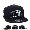 Black snapback cap with large white DBK graphic on the front panel