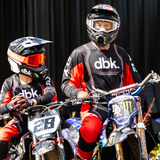 Black and red motocross jersey with gray sleeves, dbk chest logo, worn by riders