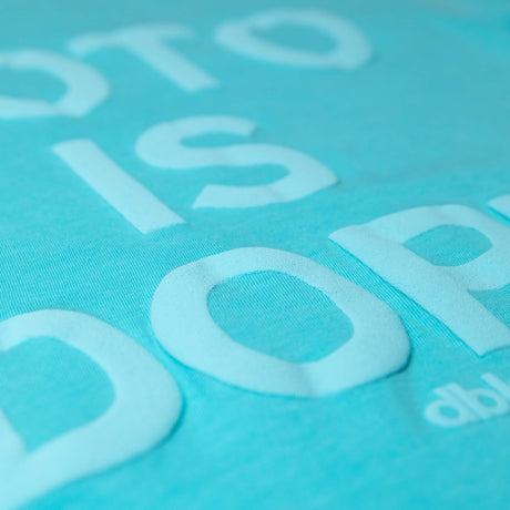 Teal T-shirt fabric detail with white “Moto is Dope” lettering print texture.