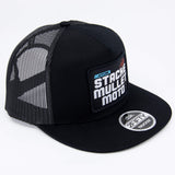 Black trucker cap with mesh side panel and back logo patch, curved brim.