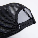 Close-up of black mesh side panel on a trucker cap with small brand label.
