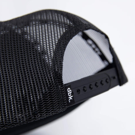 Black trucker cap mesh side panel close-up with small AP7/DBK label